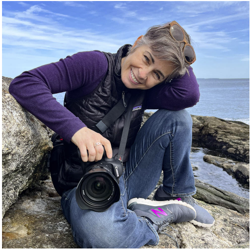 Photographer Emily Sterne smiling with her camera in her lap outside