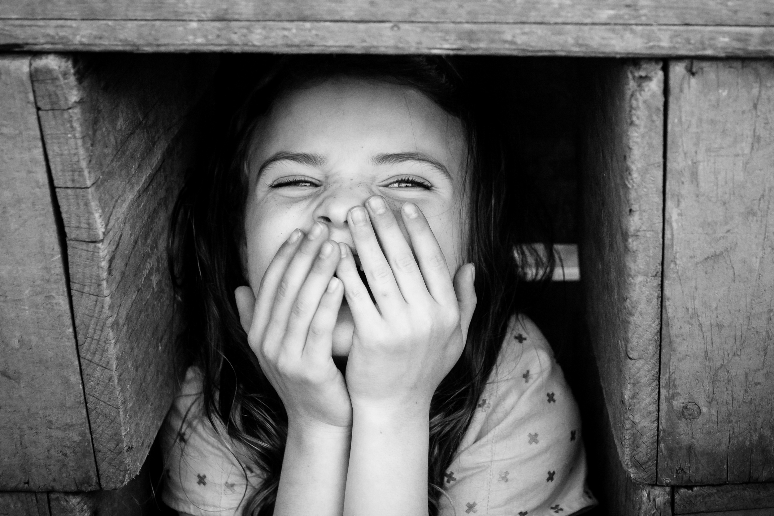 Black and white photo of a girl playing hide and seek in Cambridge, MA by Emily Sterne Photography