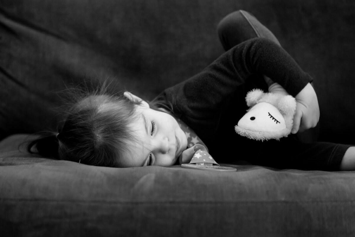 little girl rests quietly on the couch with her sleepy sheep slippers on