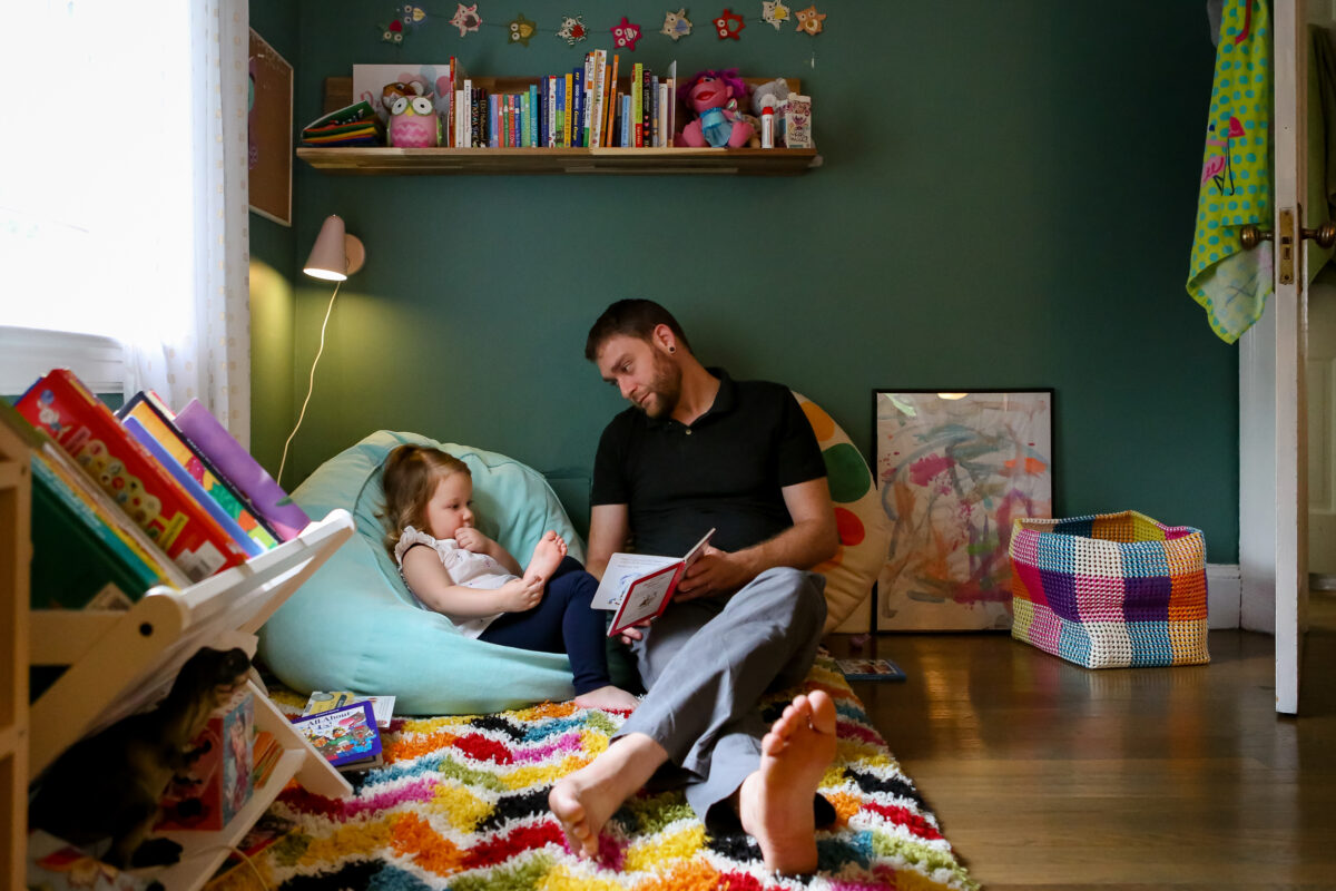 dad and daughter read together on the floor in her room