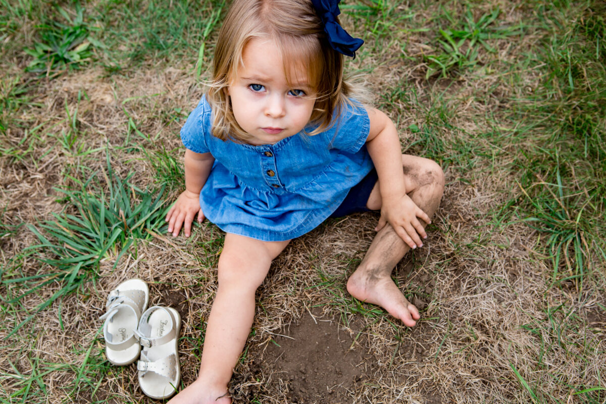 little girl wearing a dress is playing in the dirt