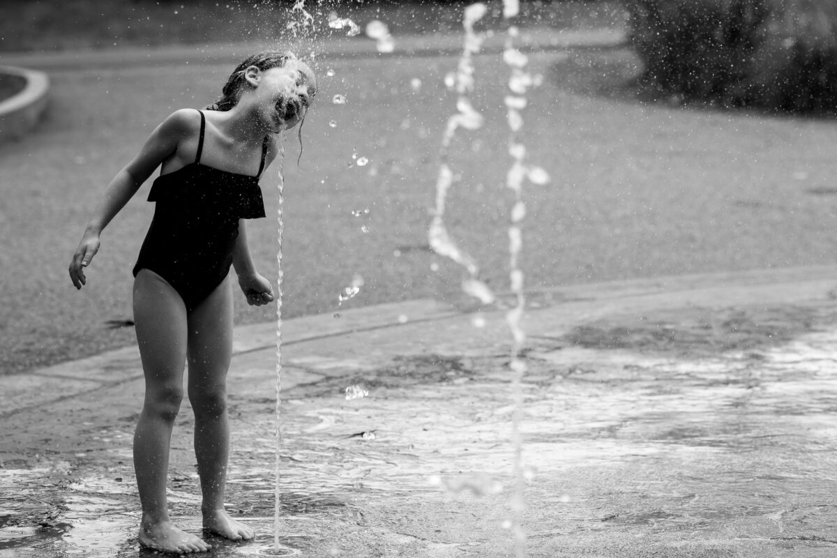 child plays in a splash pad in cambridge, ma