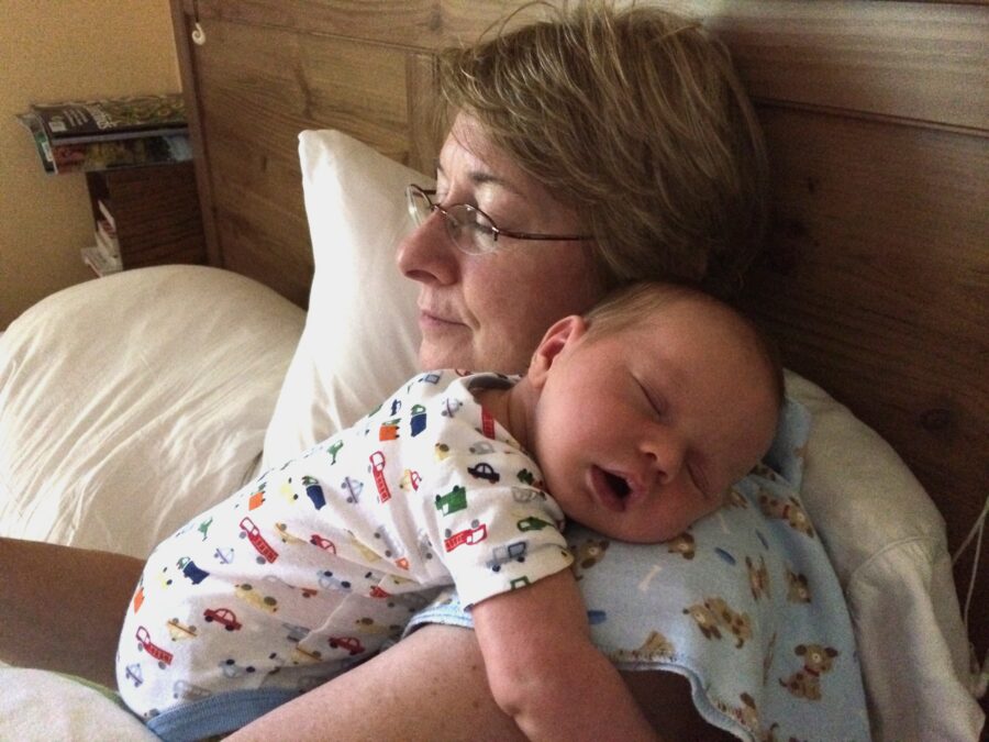 grandmother rests with sleeping infant on her shoulder